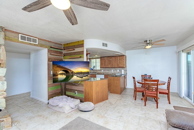 kitchen with dishwasher, sink, backsplash, ceiling fan, and a textured ceiling