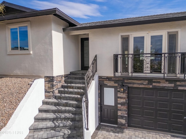 property entrance featuring a garage, stone siding, and stucco siding