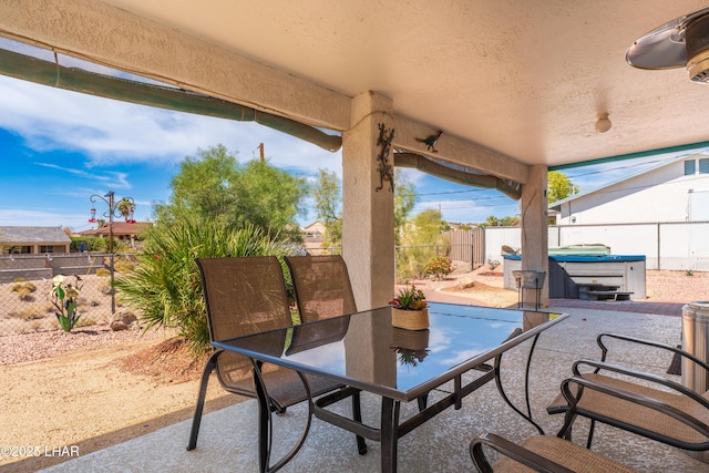 view of patio / terrace with outdoor dining space, a fenced backyard, and a hot tub