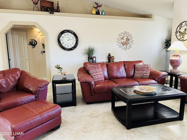 living area with arched walkways, light tile patterned flooring, and vaulted ceiling