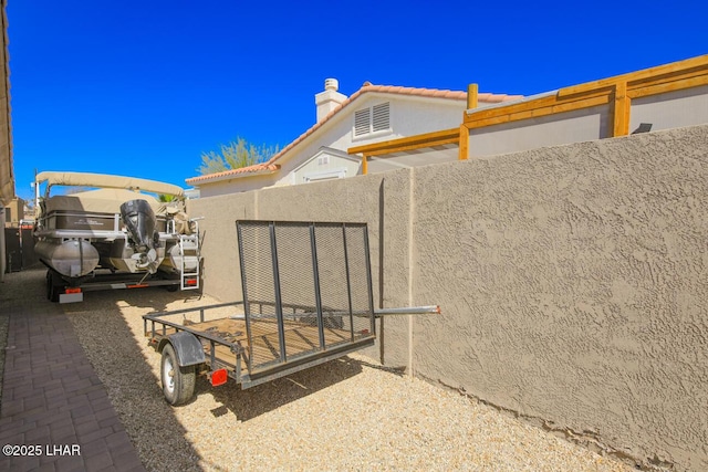 exterior space with stucco siding, a tile roof, and fence