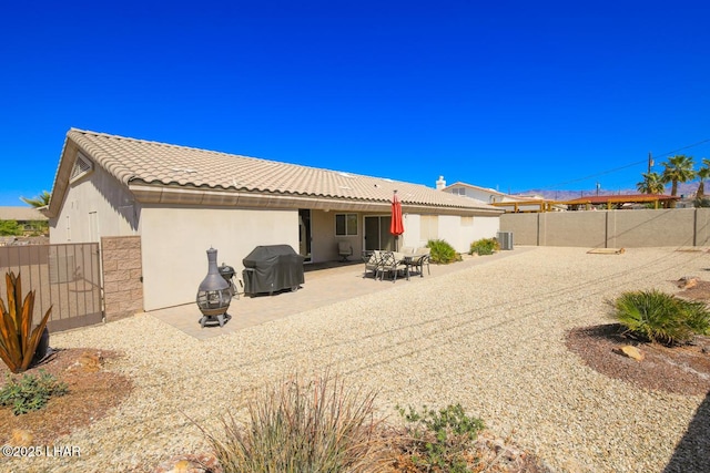 back of house featuring stucco siding, a patio, a tile roof, and a fenced backyard