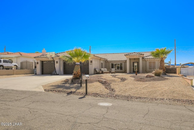 view of front of property with fence, driveway, an attached garage, stucco siding, and a tiled roof