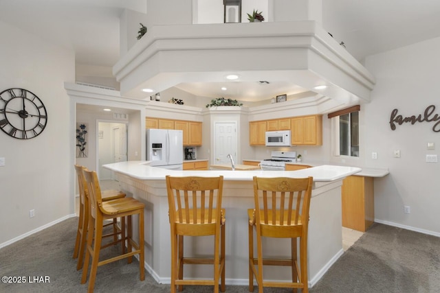 kitchen featuring light brown cabinets, light countertops, carpet floors, a large island, and white appliances