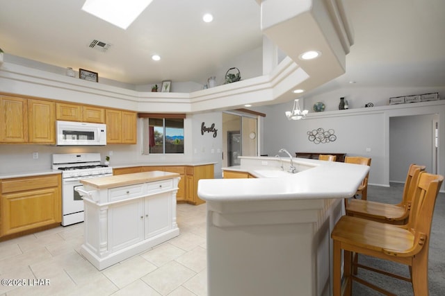 kitchen featuring visible vents, a center island with sink, white appliances, and a sink