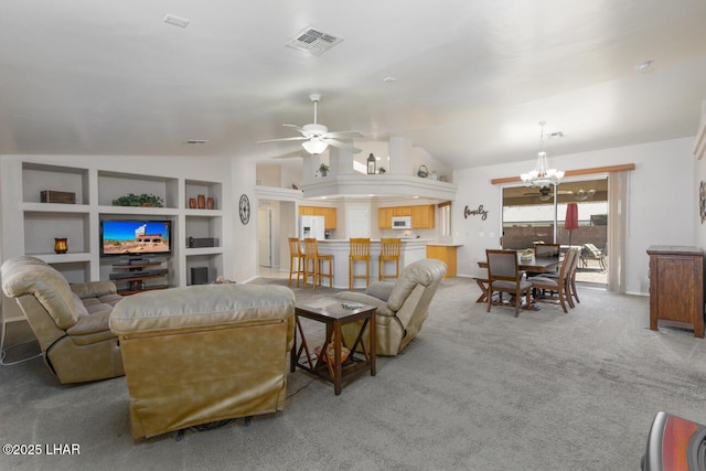 living room with built in features, visible vents, vaulted ceiling, light carpet, and ceiling fan with notable chandelier