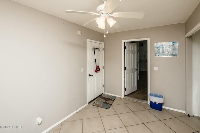 interior space featuring light tile patterned floors, a ceiling fan, and baseboards