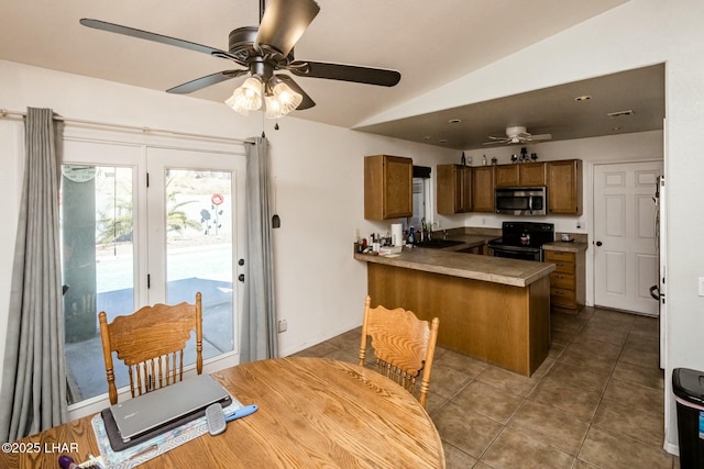 kitchen with a peninsula, black range with electric stovetop, a sink, brown cabinets, and stainless steel microwave