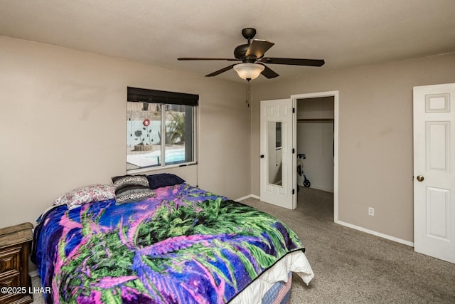 carpeted bedroom featuring a closet, baseboards, a walk in closet, and a ceiling fan