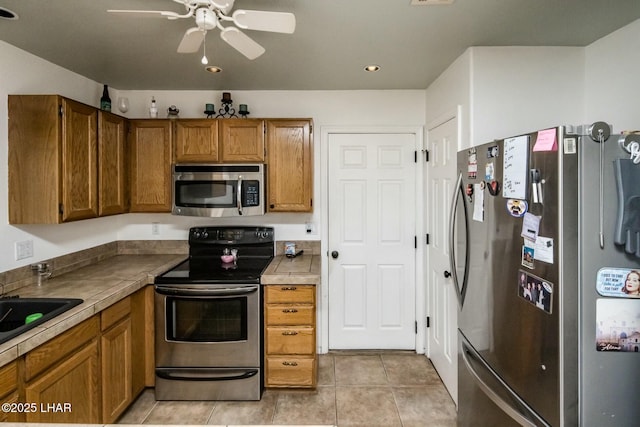 kitchen featuring brown cabinets, visible vents, appliances with stainless steel finishes, a ceiling fan, and light tile patterned flooring