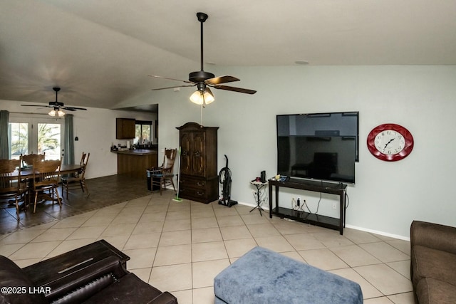 living room with baseboards, vaulted ceiling, a ceiling fan, and light tile patterned flooring