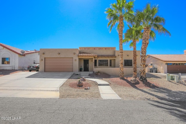 view of front facade with a garage, concrete driveway, a tile roof, and stucco siding