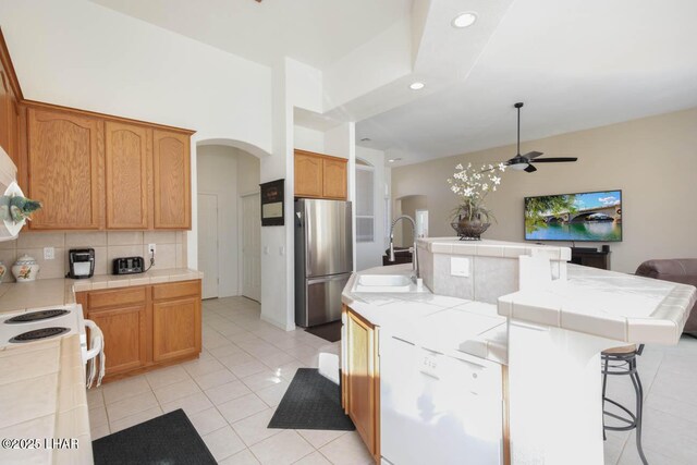 kitchen with tile counters, stainless steel fridge, and sink