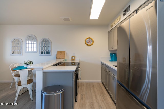 kitchen featuring a peninsula, appliances with stainless steel finishes, gray cabinets, and light countertops