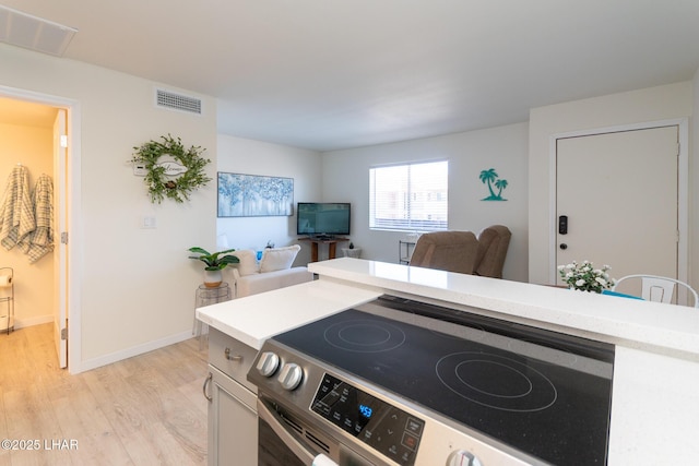 kitchen with light wood finished floors, electric range, visible vents, and open floor plan