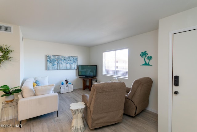 living area with baseboards, visible vents, and wood finished floors