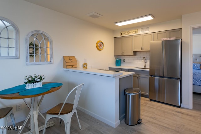 kitchen with visible vents, gray cabinets, a sink, and freestanding refrigerator