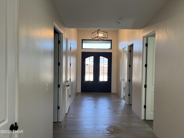 entryway with a notable chandelier, wood finished floors, and french doors