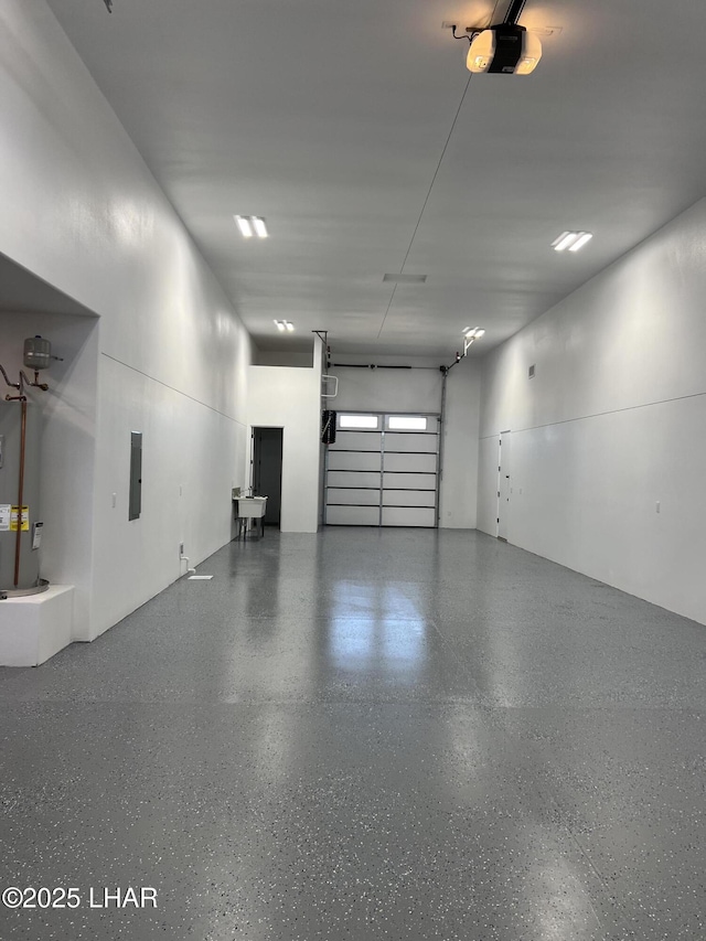 garage with electric panel, a garage door opener, and electric water heater