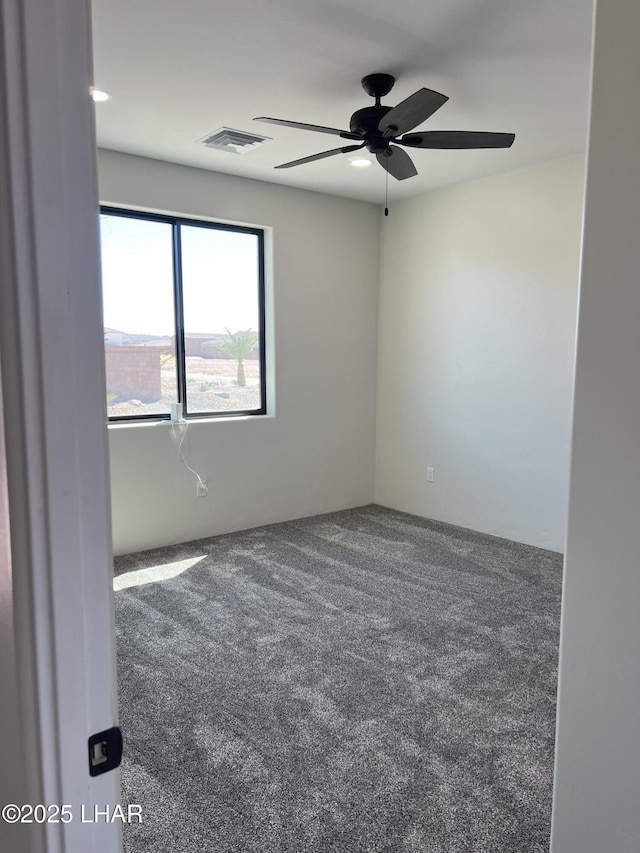 carpeted empty room featuring visible vents and ceiling fan