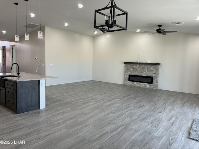 unfurnished living room with visible vents, a fireplace, light wood-style floors, a ceiling fan, and a sink