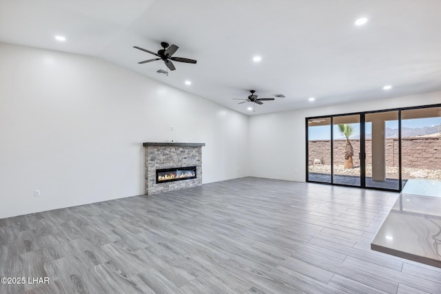 4801 N Diana Ave, Lake Havasu City, AZ 86404 - unfurnished living room with ceiling fan, a stone fireplace, vaulted ceiling, recessed lighting, and light wood-style floors