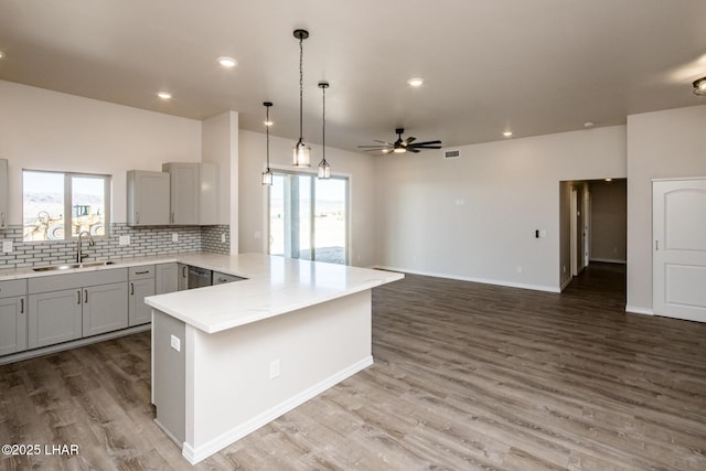 kitchen featuring gray cabinetry, light stone counters, decorative light fixtures, backsplash, and sink