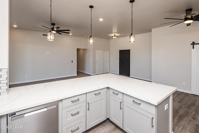 kitchen featuring white cabinetry, a barn door, light stone counters, dishwasher, and pendant lighting