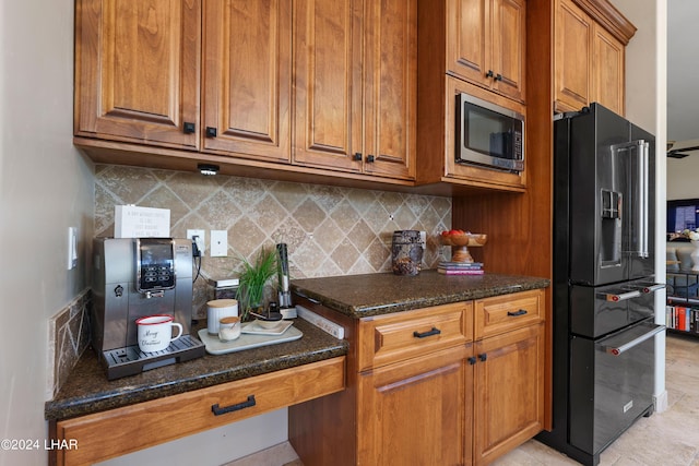 kitchen with tasteful backsplash, black fridge with ice dispenser, and dark stone countertops