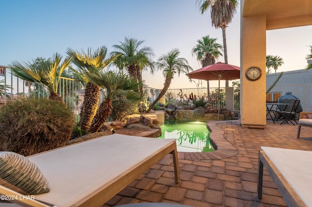 patio terrace at dusk featuring a fenced in pool