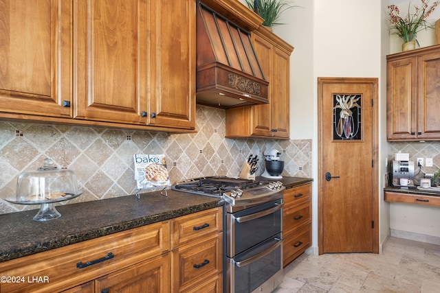 kitchen featuring premium range hood, double oven range, backsplash, and dark stone counters