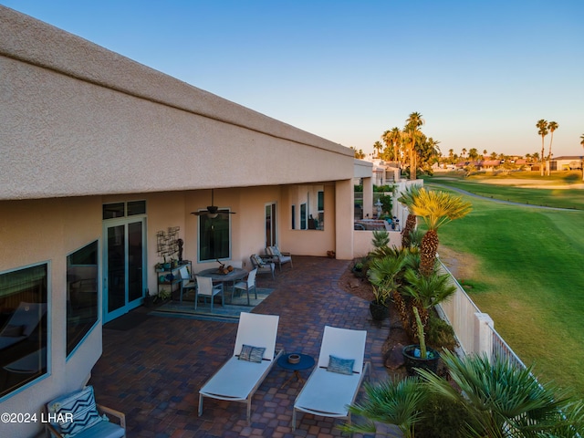 patio terrace at dusk featuring a yard and ceiling fan