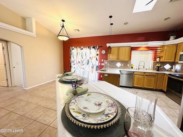 kitchen with arched walkways, stainless steel appliances, a sink, tasteful backsplash, and pendant lighting