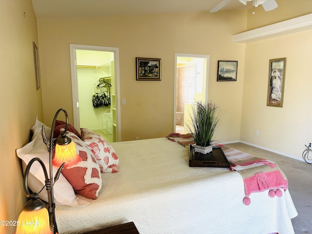 carpeted bedroom with ceiling fan, ensuite bath, baseboards, and a walk in closet