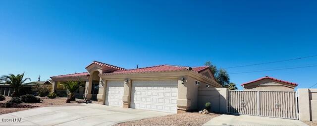 view of front facade featuring an attached garage, a tile roof, a gate, and concrete driveway