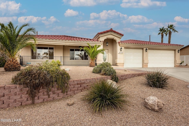 mediterranean / spanish-style home with driveway, an attached garage, a tiled roof, and stucco siding