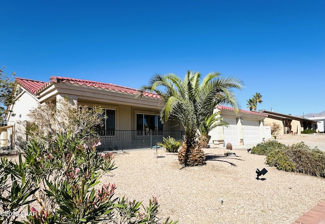 mediterranean / spanish-style home featuring an attached garage, stucco siding, and a tiled roof