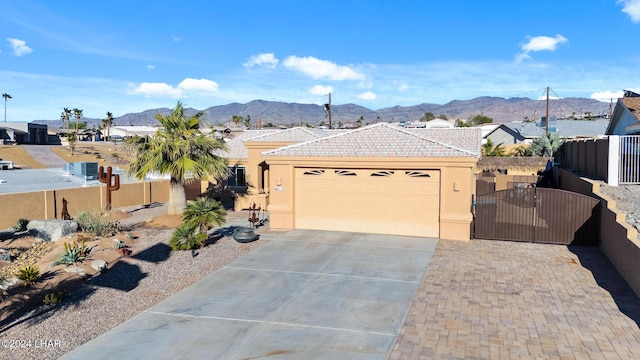 view of front of home with stucco siding, driveway, a tile roof, a gate, and a mountain view