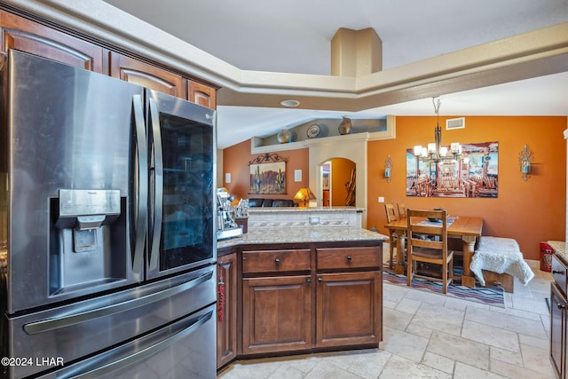 kitchen featuring stone tile floors, visible vents, arched walkways, vaulted ceiling, and stainless steel refrigerator with ice dispenser