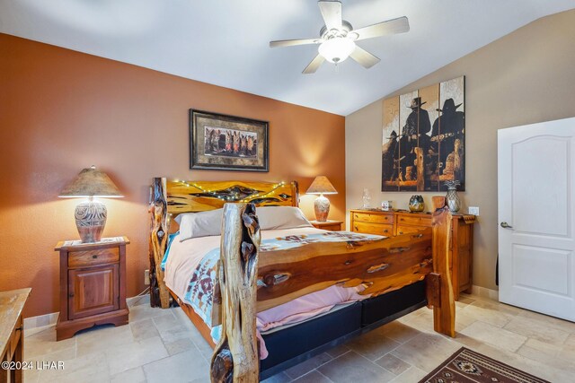 bedroom featuring stone tile flooring, a ceiling fan, baseboards, and vaulted ceiling