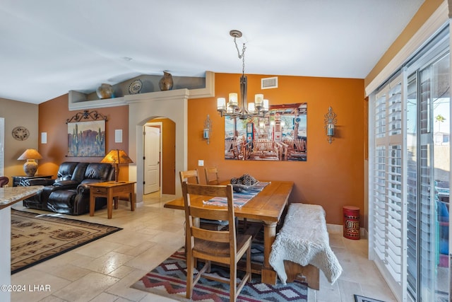 dining area with visible vents, lofted ceiling, stone tile floors, an inviting chandelier, and arched walkways