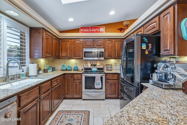 kitchen featuring stone tile floors, backsplash, stainless steel appliances, and a sink