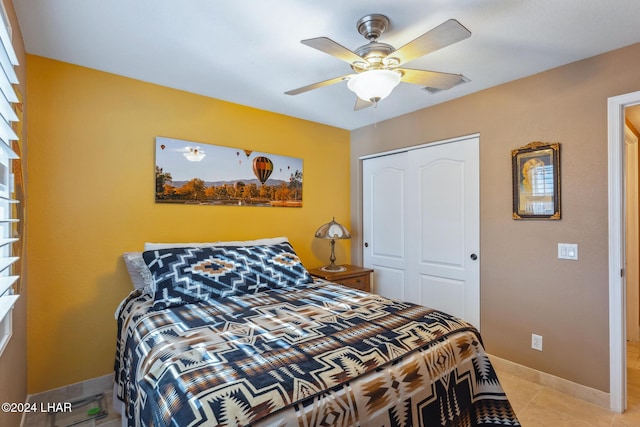 bedroom featuring light tile patterned floors, baseboards, a closet, and ceiling fan