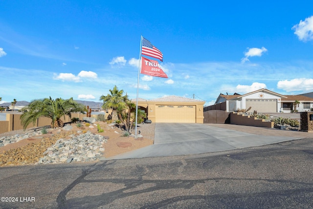 view of front of house featuring fence, a garage, driveway, and stucco siding