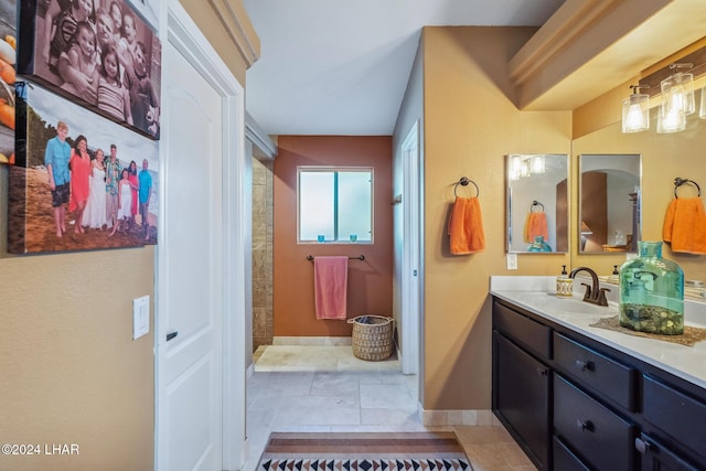 full bathroom with vanity, baseboards, and tiled shower