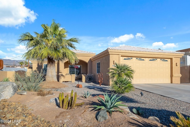 view of front facade featuring stucco siding, a tile roof, fence, concrete driveway, and a garage