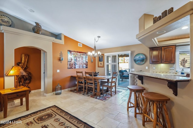 dining area with visible vents, lofted ceiling, stone tile flooring, arched walkways, and baseboards