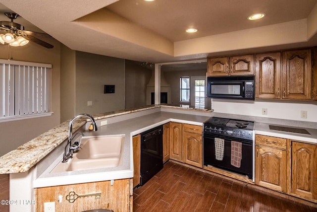 kitchen featuring sink, ceiling fan, black appliances, a raised ceiling, and kitchen peninsula