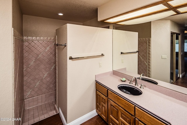 bathroom with vanity, hardwood / wood-style floors, a textured ceiling, and a tile shower