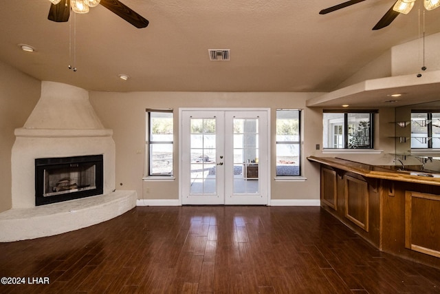 unfurnished living room featuring vaulted ceiling, a large fireplace, ceiling fan, dark wood-type flooring, and french doors